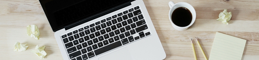 Close up of a desk with notes, computer, and black coffee