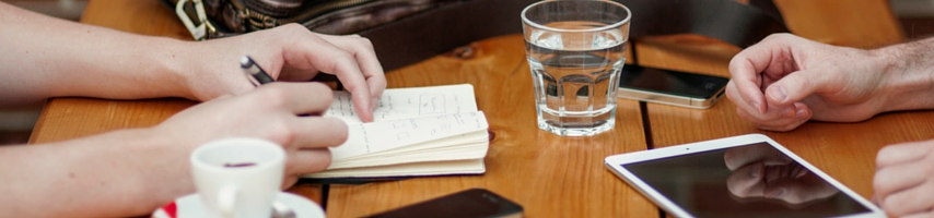 person taking notes during a meeting at a cafe