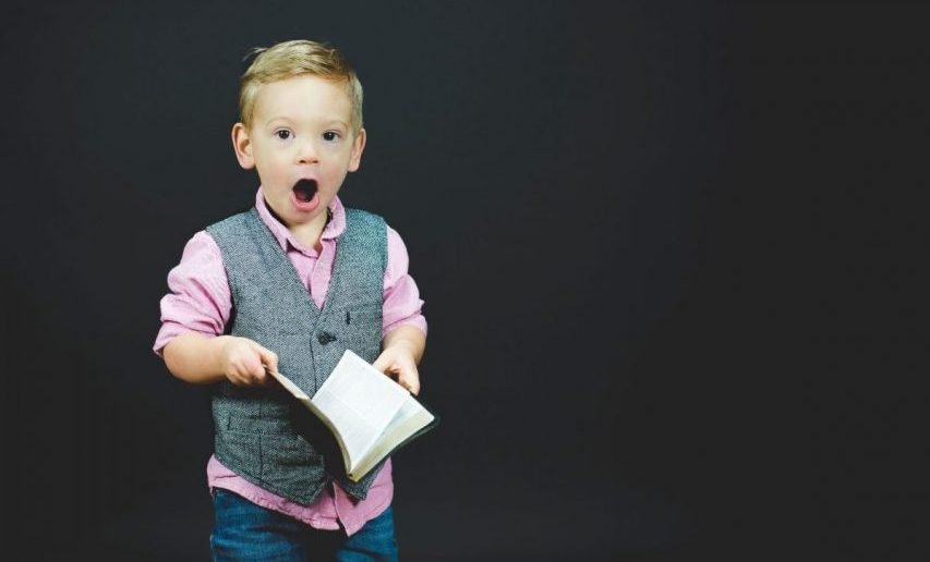 kid holding a book with a shocked look on his face